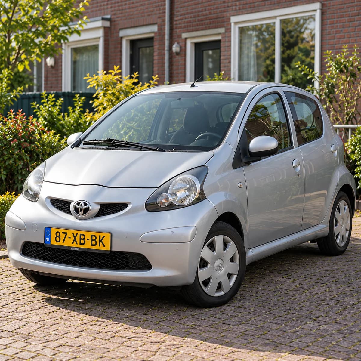 A silver Toyota Aygo on a driveway in a Dutch neighbourhood